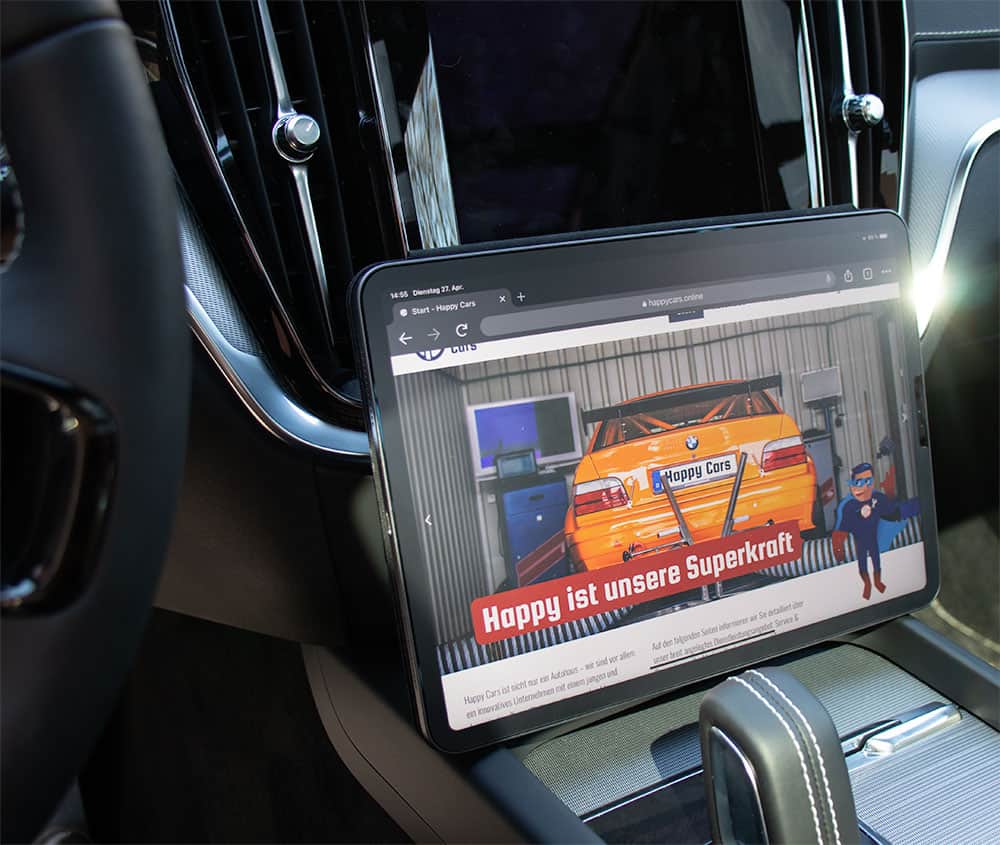 Man sieht ein Tablet in einem Auto, auf dessen Bildschirm die Webseite der Firma Happy Cars abgebildet ist.